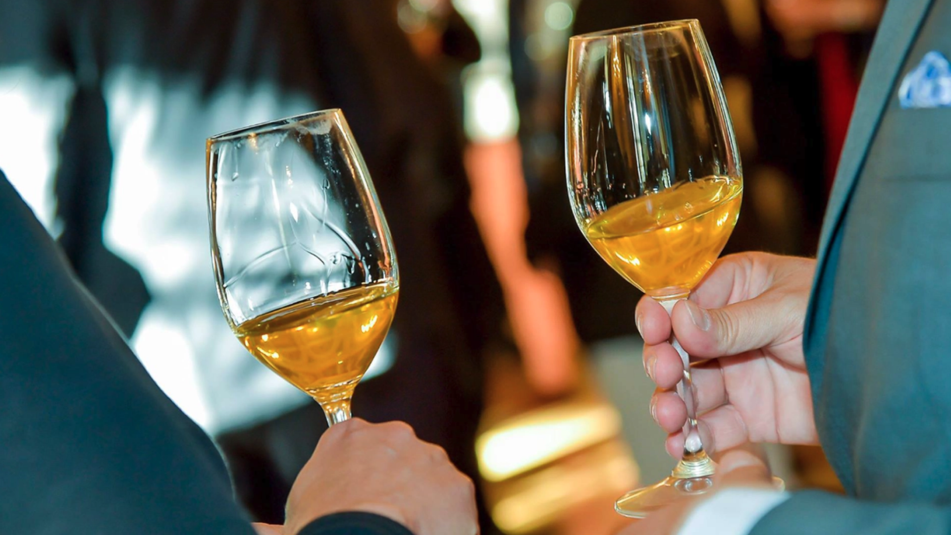 Proosten met dessertwijn tijdens een evenement Twee glazen dessertwijn in de hand tijdens een proeverij of evenement, symbolisch voor proosten en gezellig samenzijn