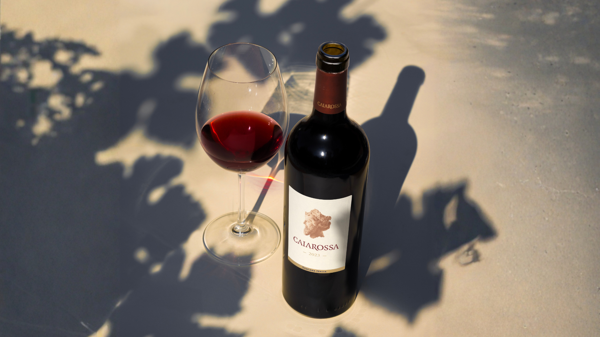 Fles Caiarossa met gevuld glas ernaast in de schaduw